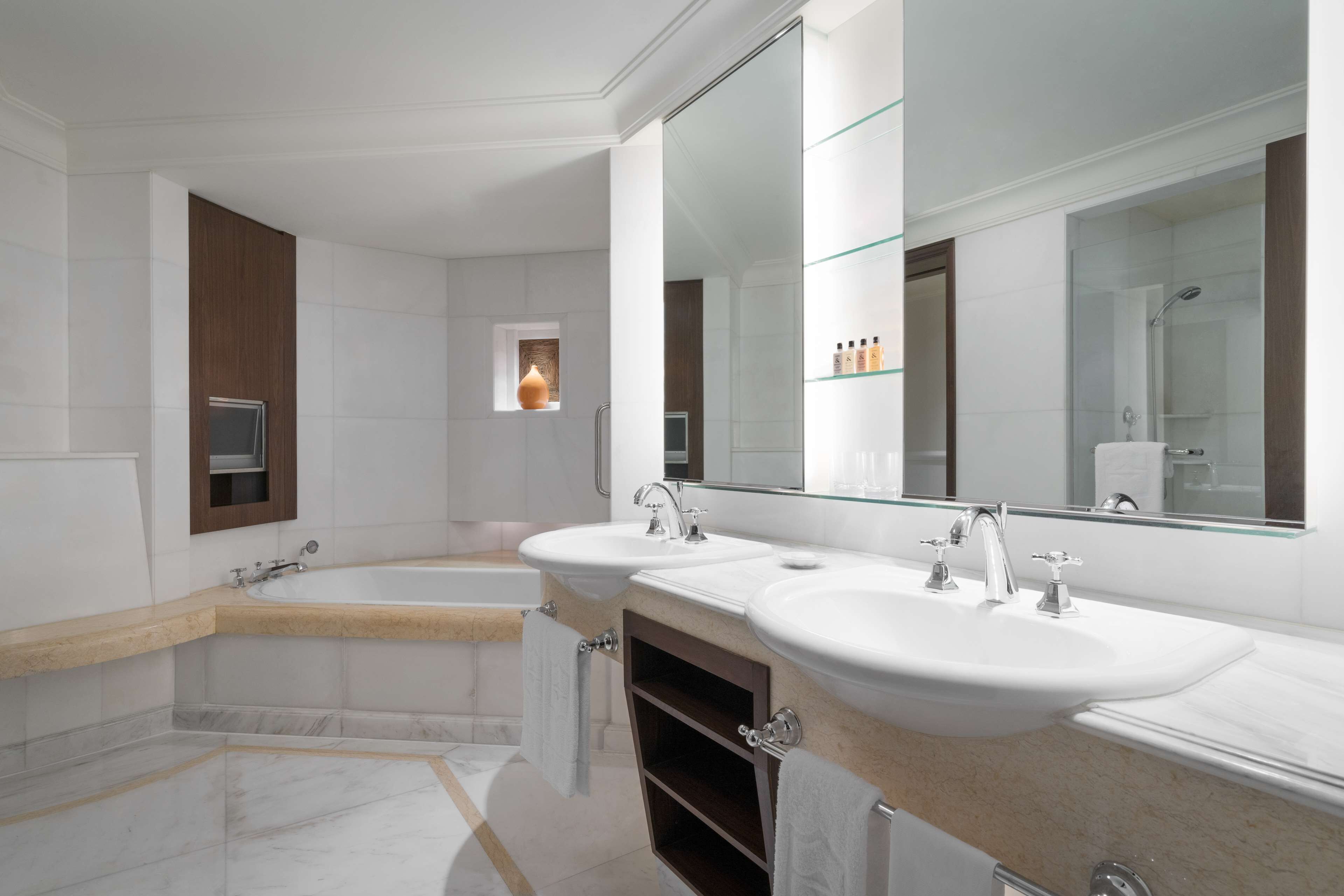 A modern bathroom with two sinks, a bathtub, and a large mirror.