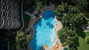 Luchtbeeld van een resort met een groot zwembad, omringd door palmbomen en loungegedeeltes.