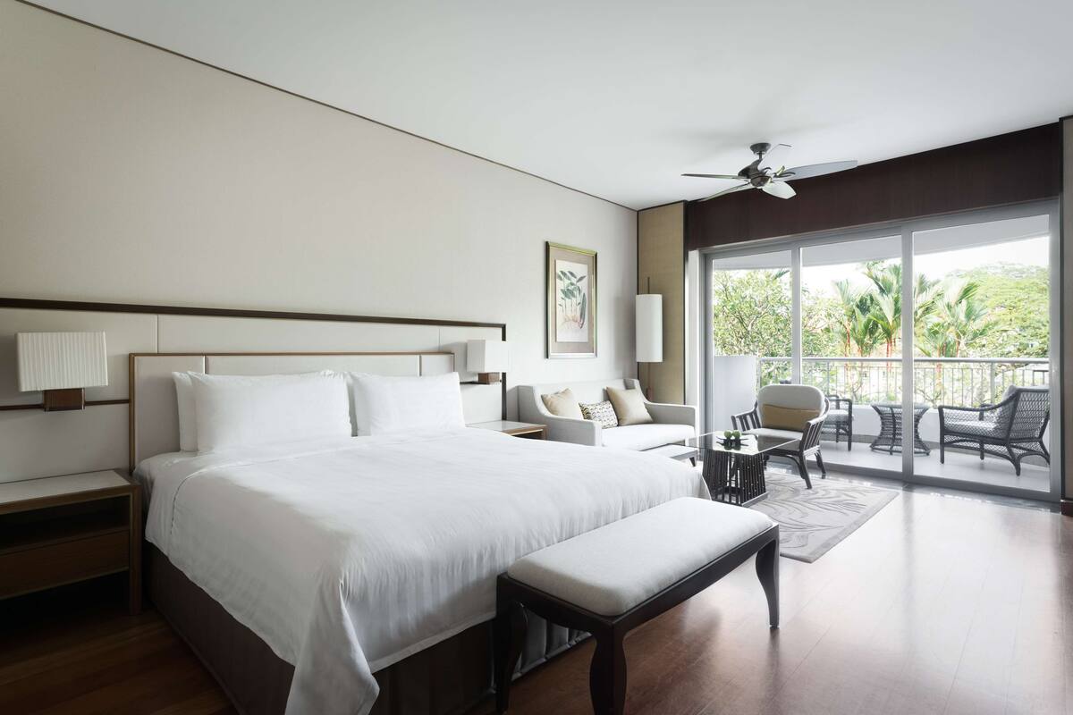 Une chambre d’hôtel dotée d’un grand lit, d’un bureau, d’une chaise et d’un balcon aménagé avec du mobilier d’extérieur.