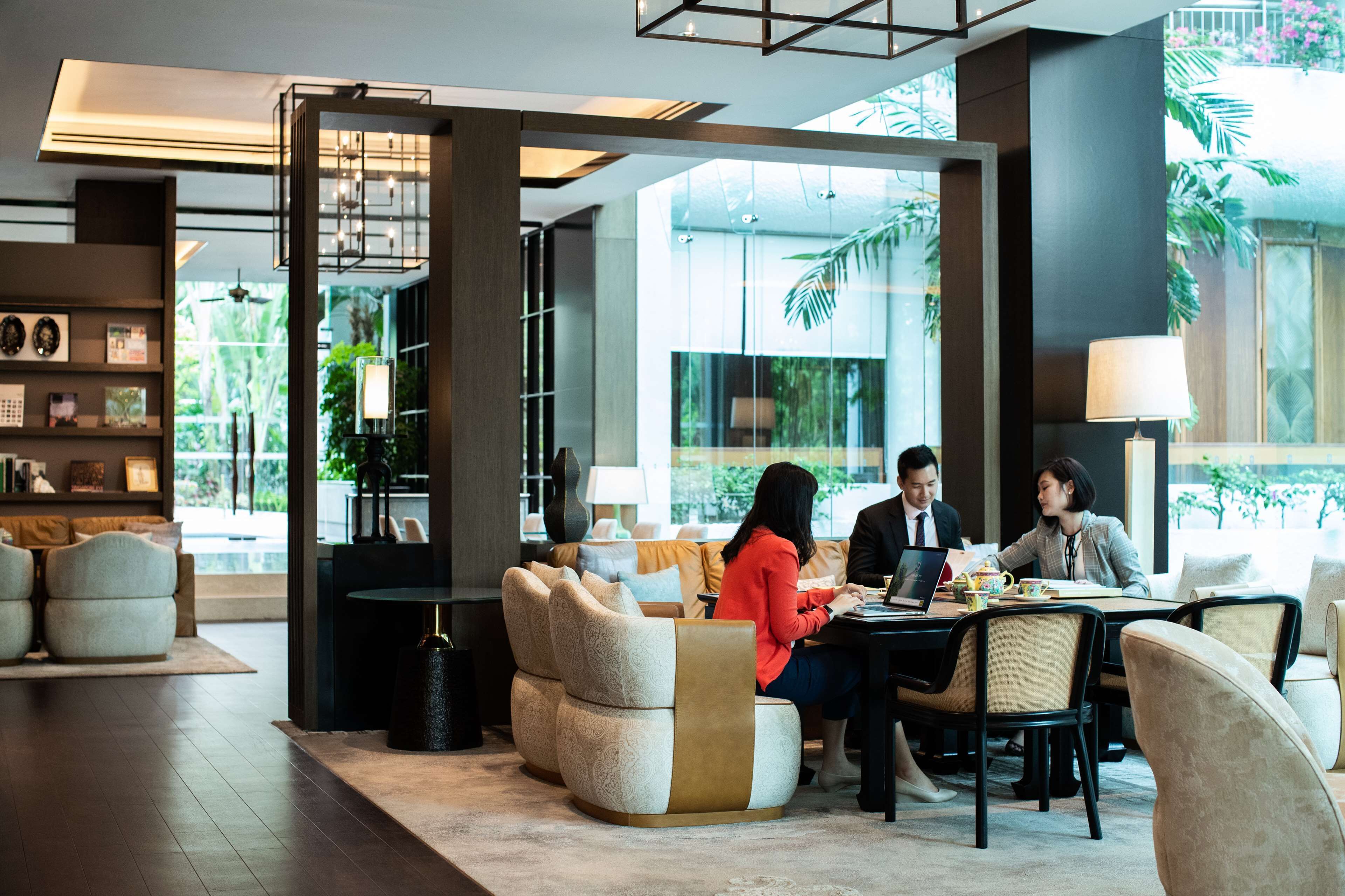 A modern lounge area with comfortable seating, a coffee table, and a large window providing a view of greenery outside.