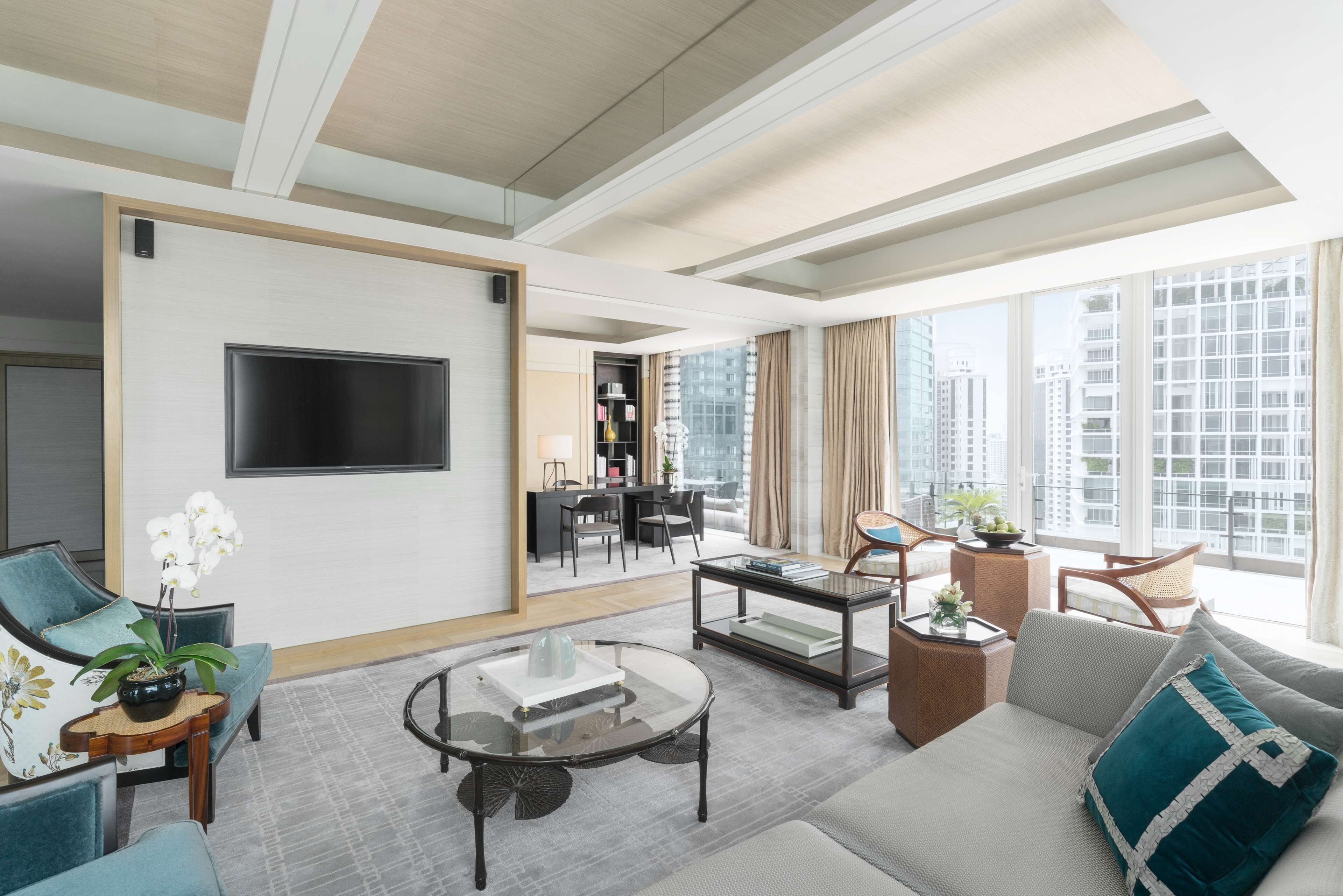 A modern living room with a sofa, armchairs, a coffee table, and a TV mounted on the wall.