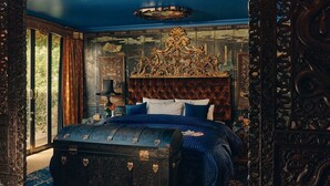 Une chambre à coucher avec un grand lit, une tête de lit décorée et une commode.