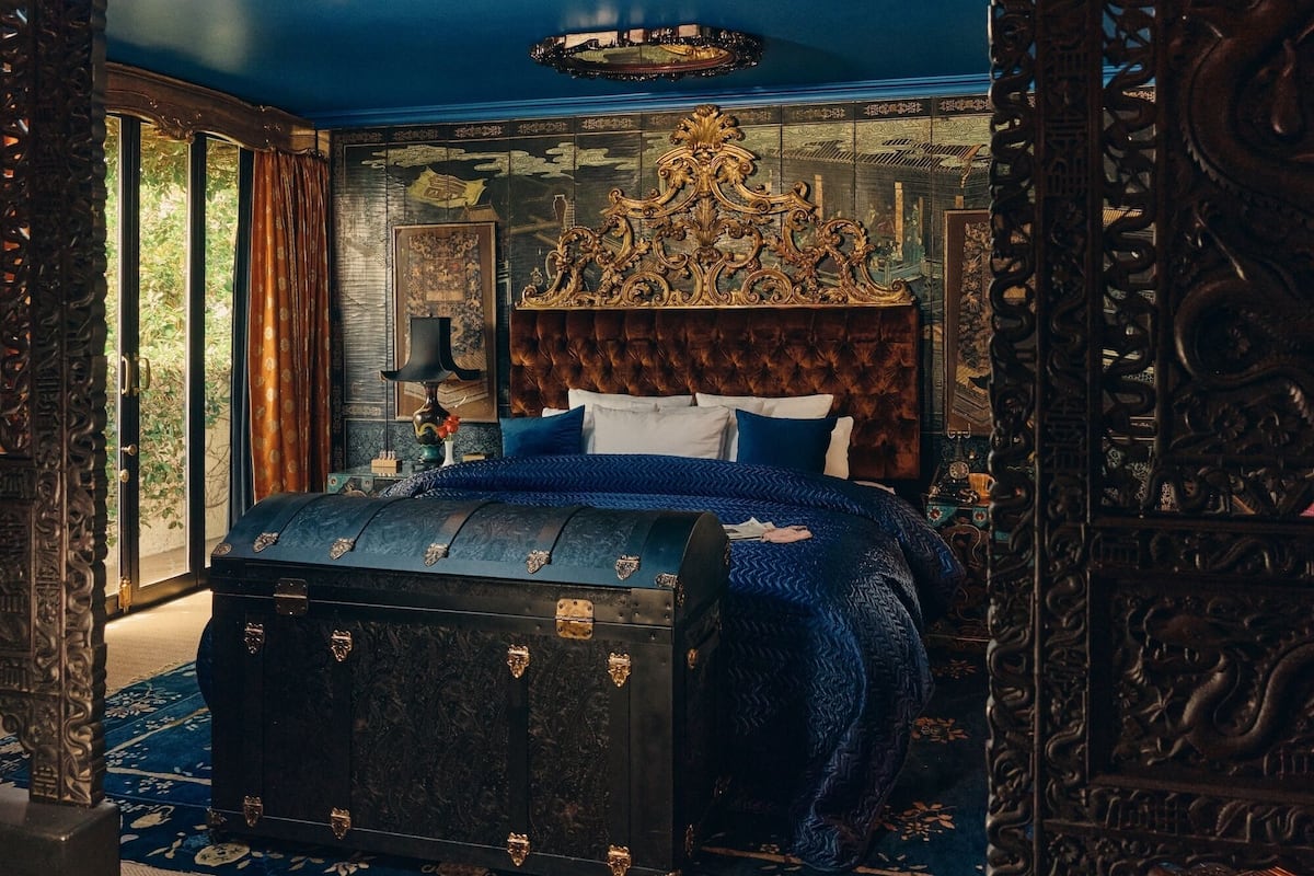 A bedroom with a large bed, ornate headboard, and a chest of drawers.
