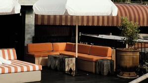 A rooftop pool area with outdoor seating, umbrellas, and a view of the city skyline. - Petit Ermitage (West Hollywood)