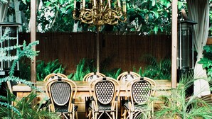An outdoor dining area with a table and chairs, surrounded by plants and a wooden fence. - Petit Ermitage (West Hollywood)