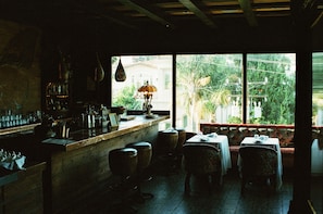 Un restaurant doté d’un bar, de tables et offrant une vue sur la verdure environnante.