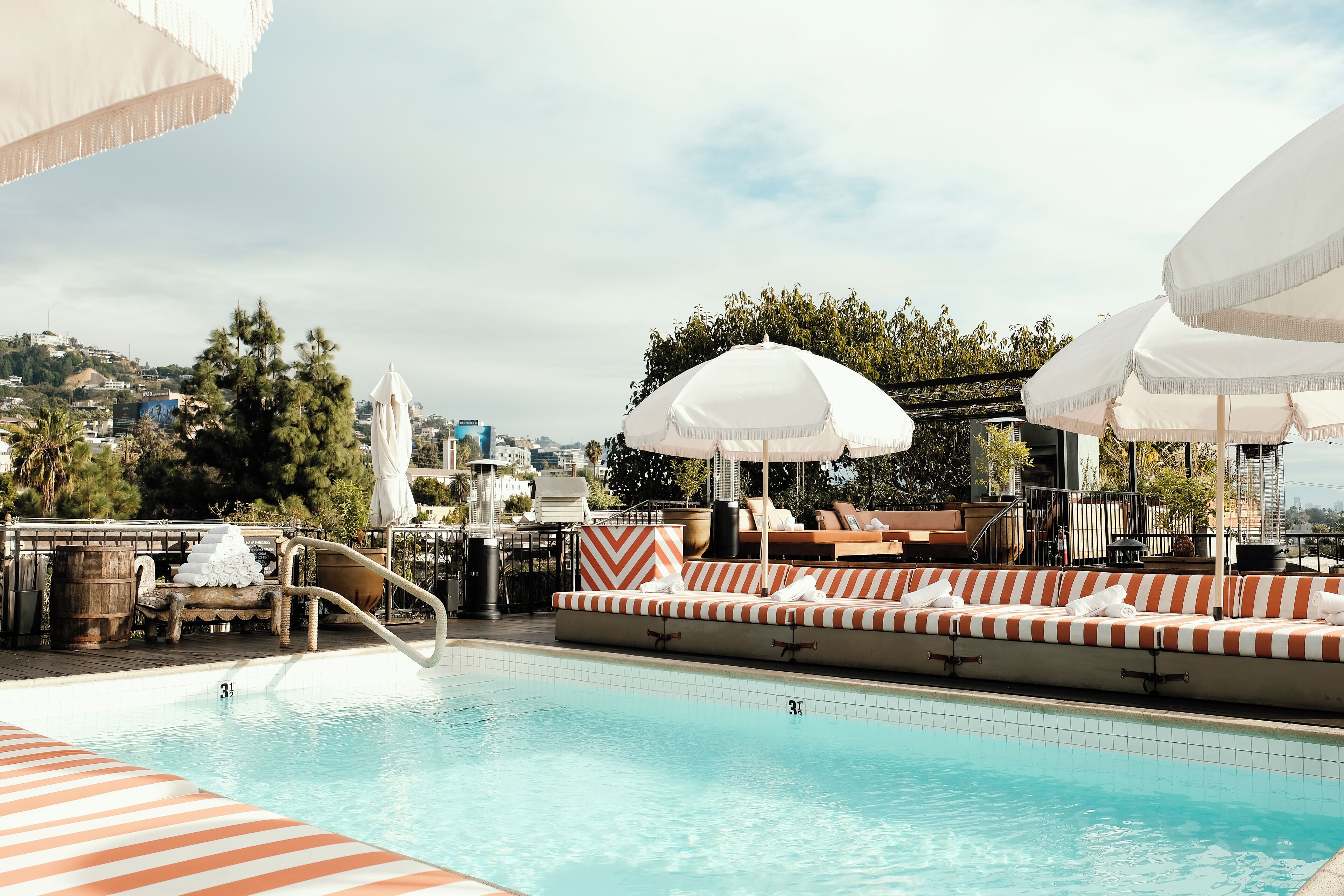 Una piscina al aire libre, sombrillas, sillones reclinables de piscina