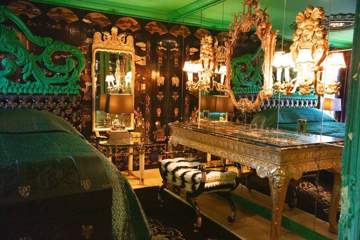 A room with ornate furniture, a large mirror, and a chandelier.