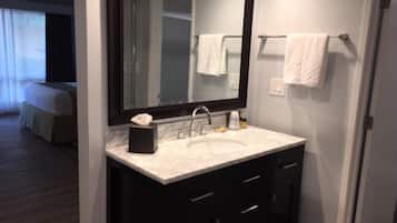 A modern bathroom with a large mirror, dark cabinetry, and a white sink.