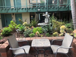 A courtyard with a statue, various plants, and a table with chairs.