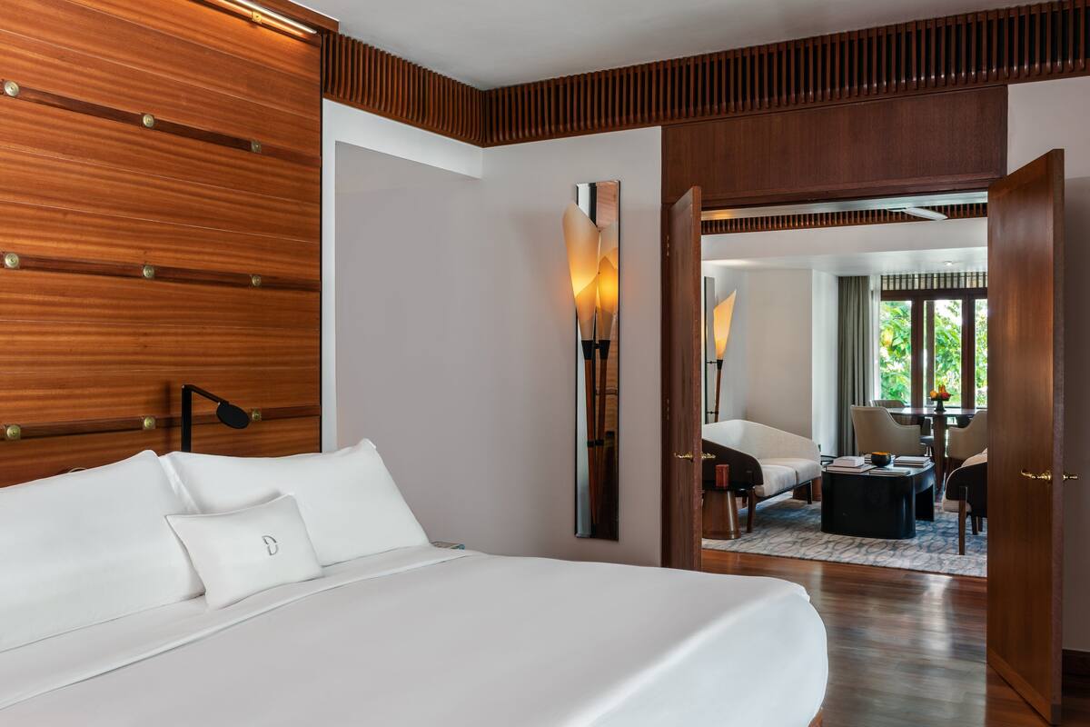 Ein modernes Hotelzimmer mit einem großen Bett, Holzvertäfelung an den Wänden, einem Nachttisch und Blick auf den Speisesaal.