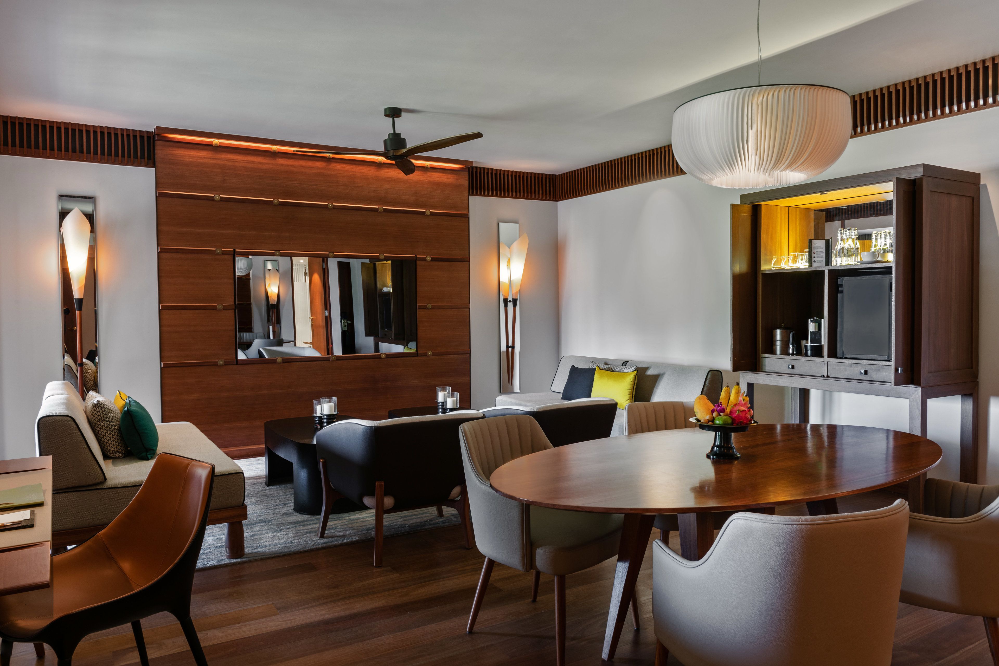 A modern living room with a wooden floor, a round dining table, and a ceiling fan.