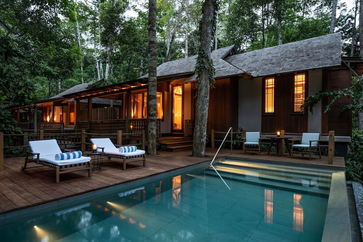 Eine Holzhütte mit Pool, Liegestühlen und einer Terrasse.