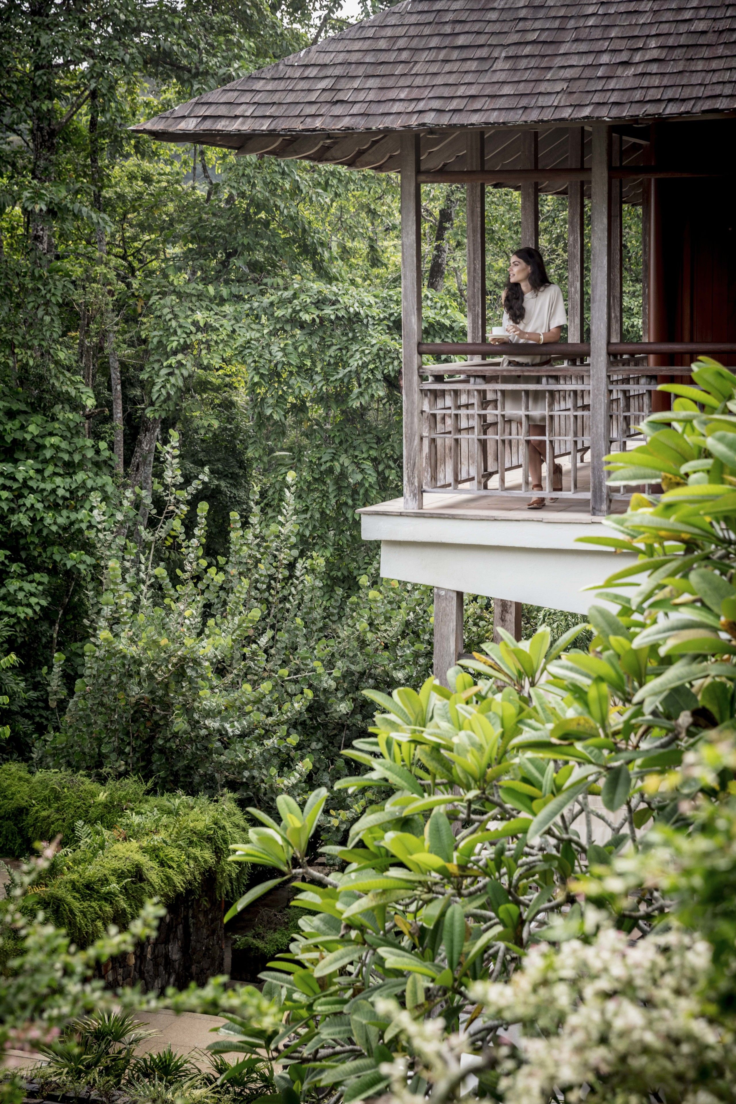 Une structure en bois dotée d’un balcon donnant sur un jardin luxuriant.