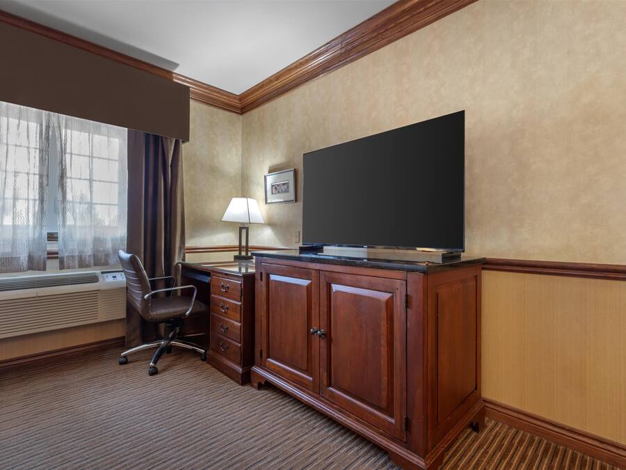 Habitación de hotel con un ventanal grande, un escritorio con silla, un televisor de pantalla plana y un armario.