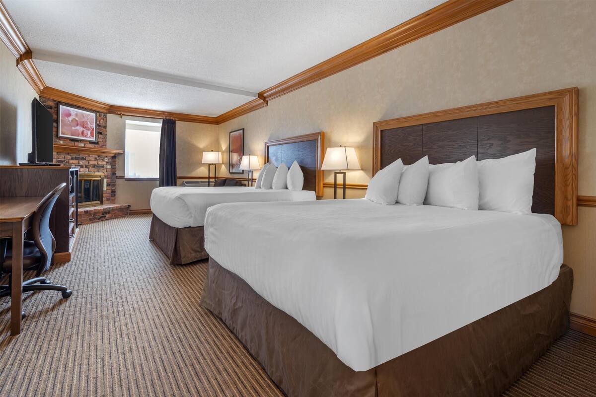 A hotel room with two beds, a desk, and a TV.