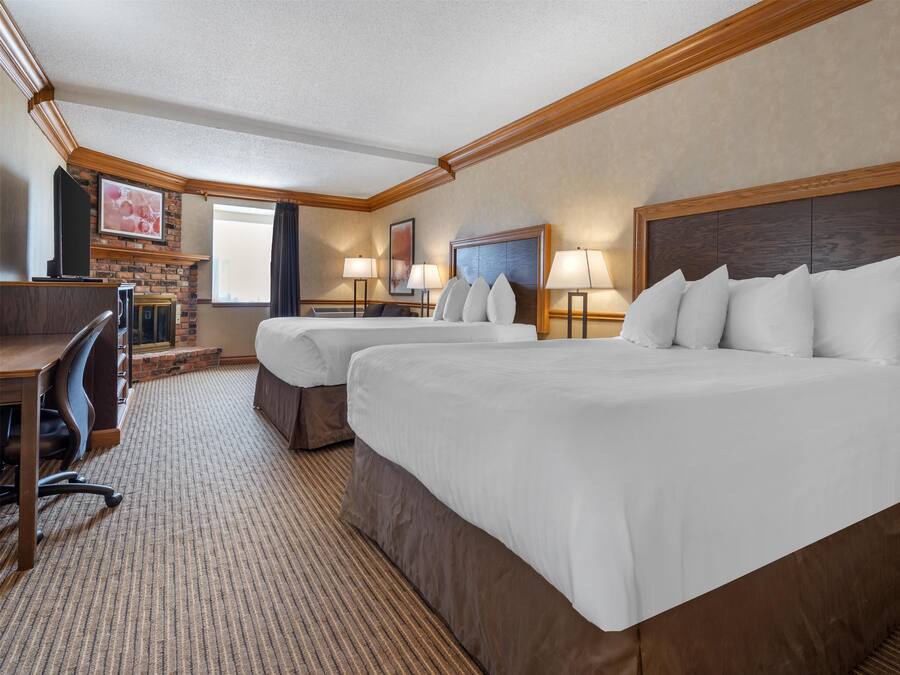 A hotel room with two beds, a desk, and a TV.