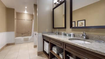 A modern bathroom with two sinks, a large mirror, and a walk-in shower.