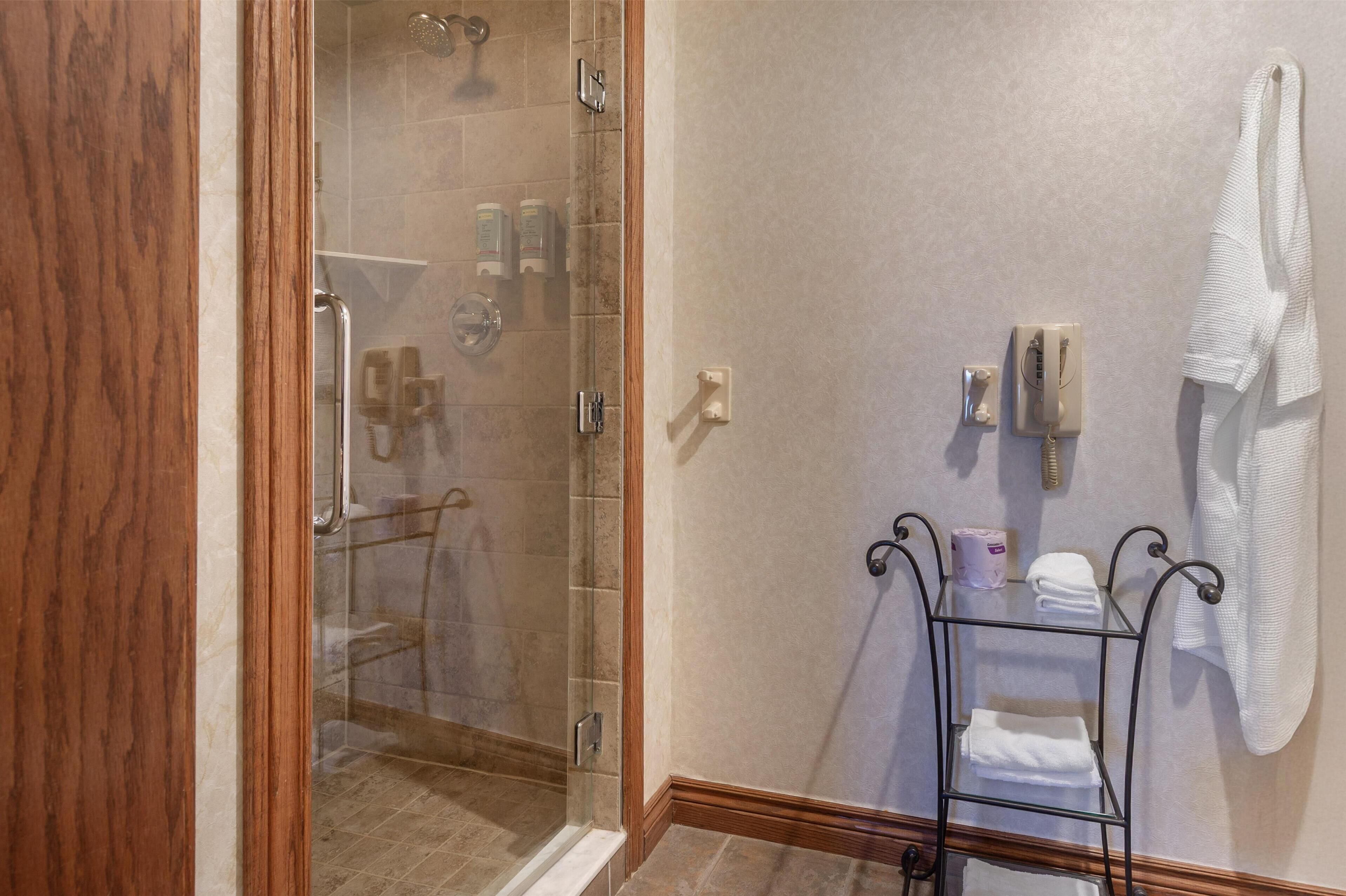 A bathroom with a glass-enclosed shower, a towel rack, and a small shelf with toiletries.