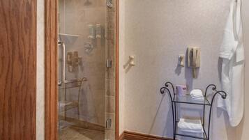 A bathroom with a glass-enclosed shower, a towel rack, and a small shelf with toiletries.