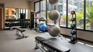A gym with exercise equipment, a bench, and a mirror. - Courtyard by Marriott Fresno (Fresno)