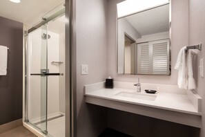 A modern bathroom with a glass-enclosed shower, a white sink, and a mirror above it. - Courtyard by Marriott Fresno (Fresno)