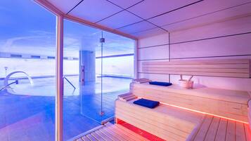 Una sauna moderna con puerta de cristal, bancos de madera y vistas a un paisaje nevado.