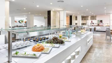 A buffet area with various food items and a kitchen in the background.