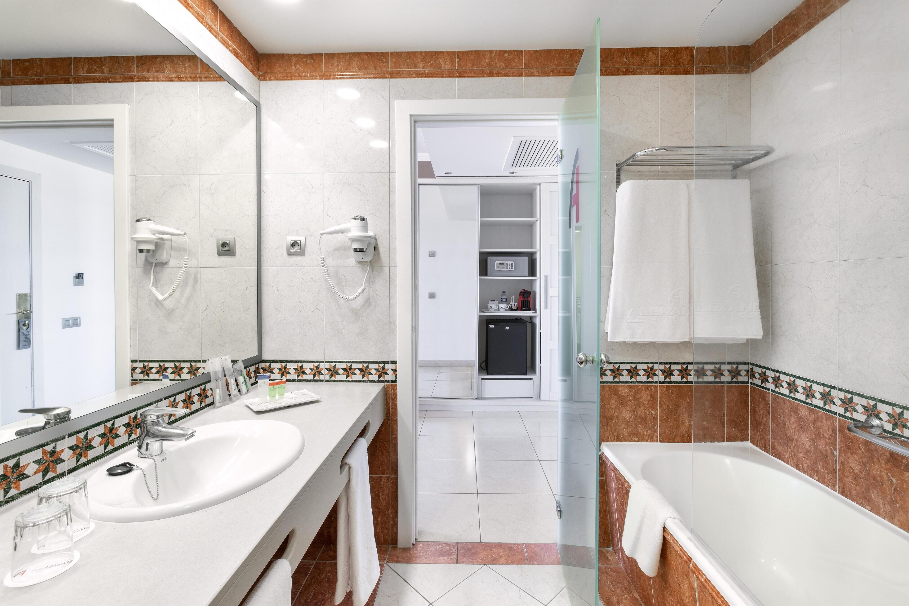 A modern bathroom with two sinks, a glass-enclosed shower, and a walk-in closet.