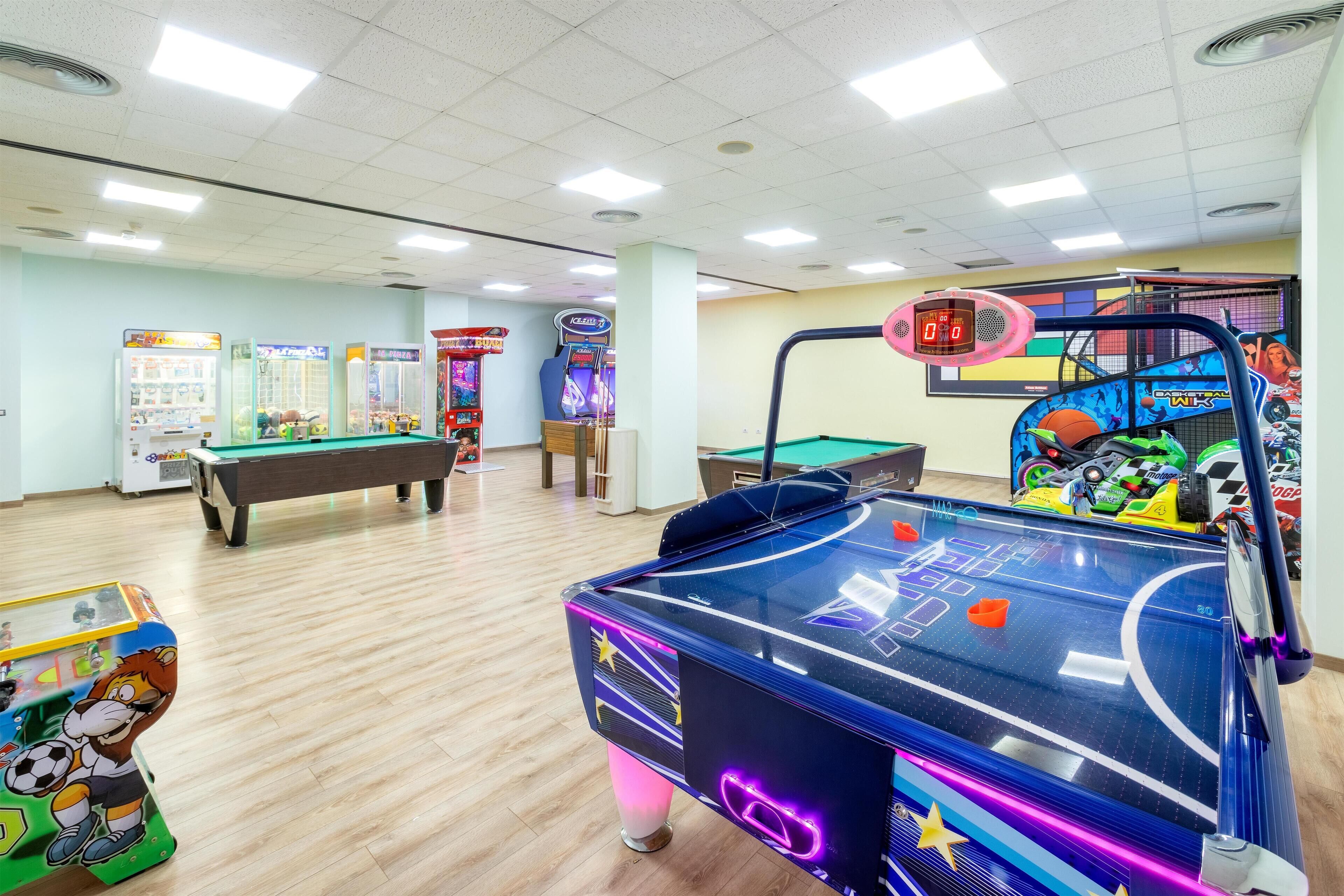 A recreational room with a pool table, foosball table, and various arcade games.