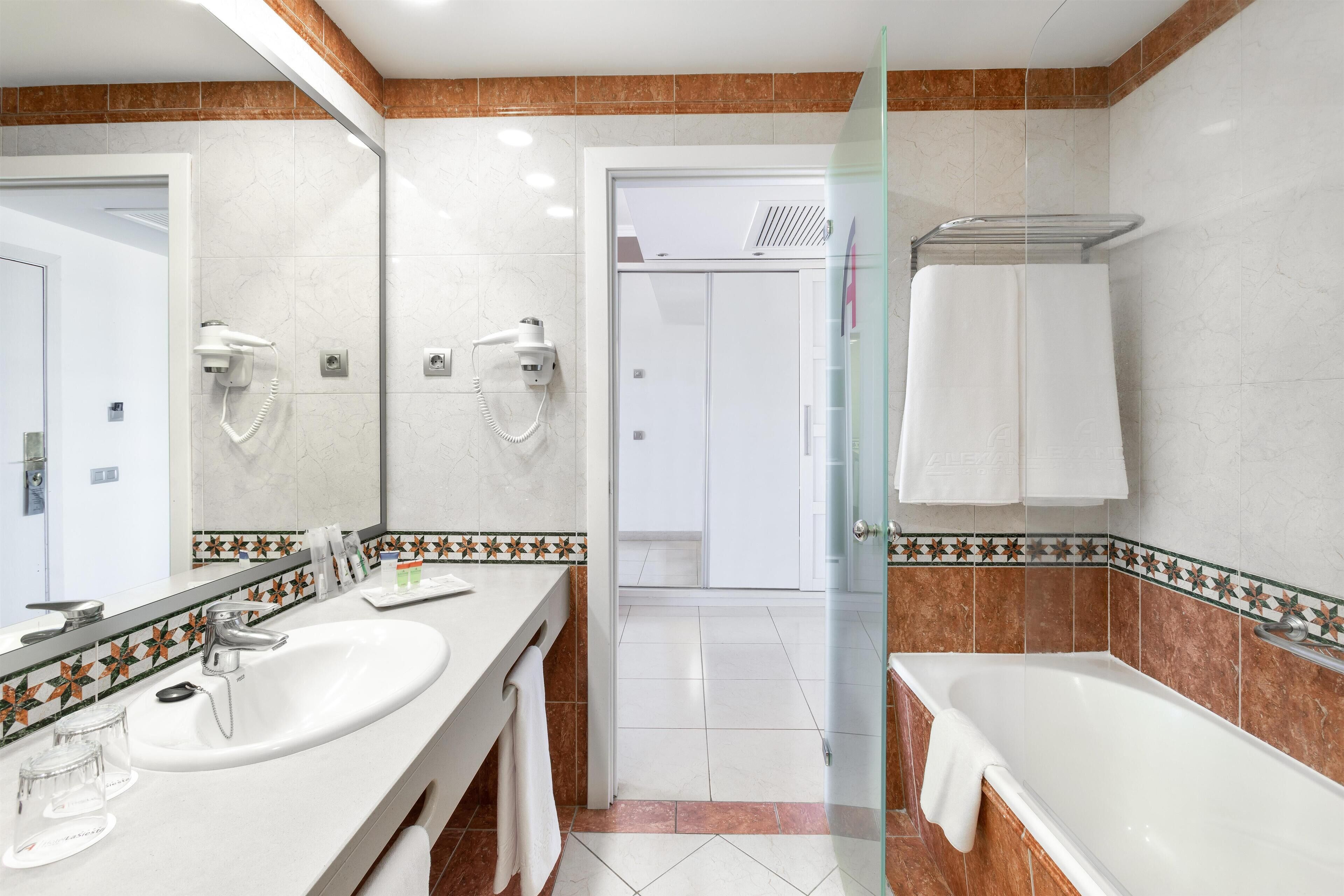 Un baño moderno con dos lavamanos, cabina de ducha de vidrio y bañera.
