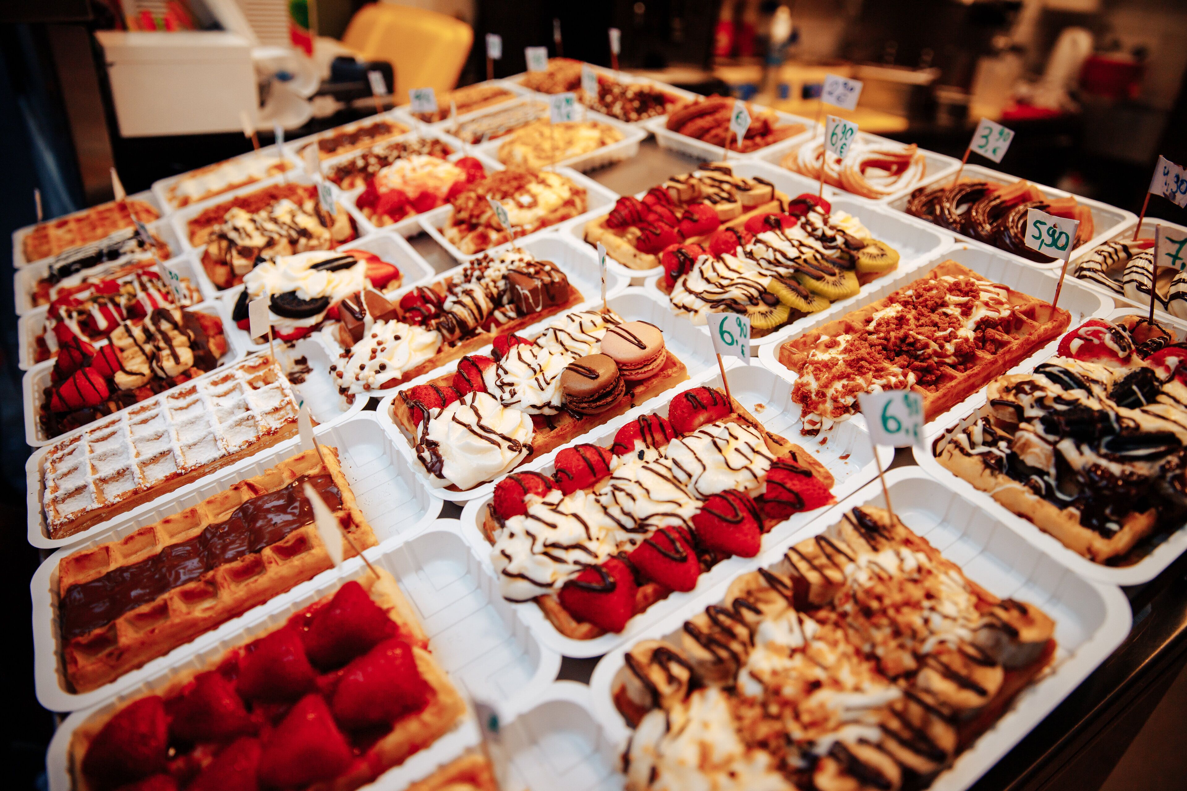 Diversas opciones de postres exhibidas en bandejas con etiquetas de precio.