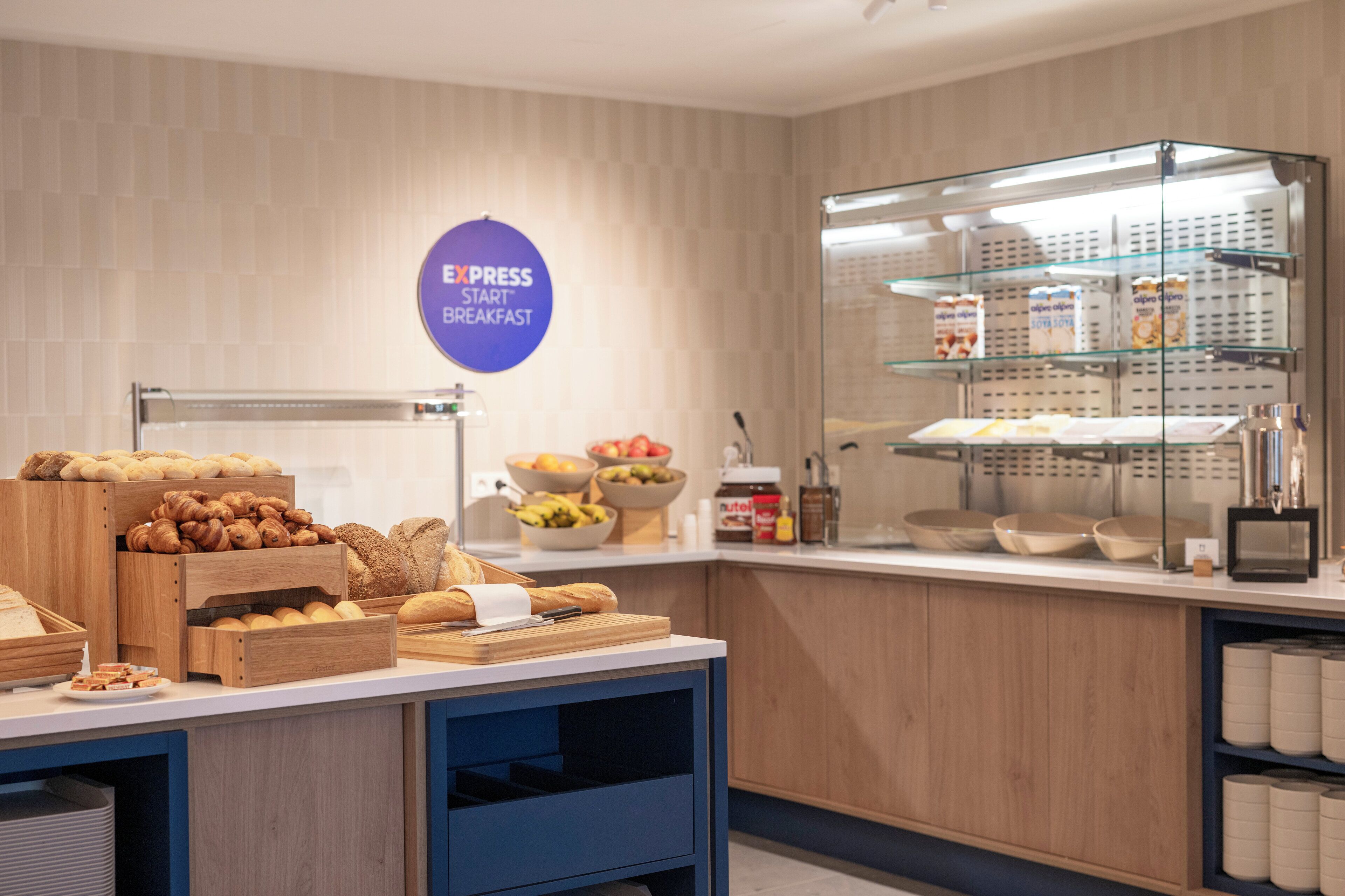 A breakfast buffet area with various breads, pastries, and fruits.