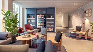 A modern lounge area with seating, a vending machine, and a wall with a map. - Holiday Inn Express & Suites Ghent by IHG (Ghent)
