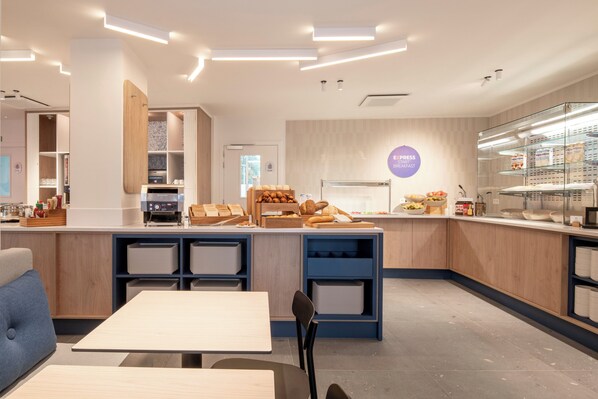 A modern café interior with a central counter, seating area, and a visible menu board.