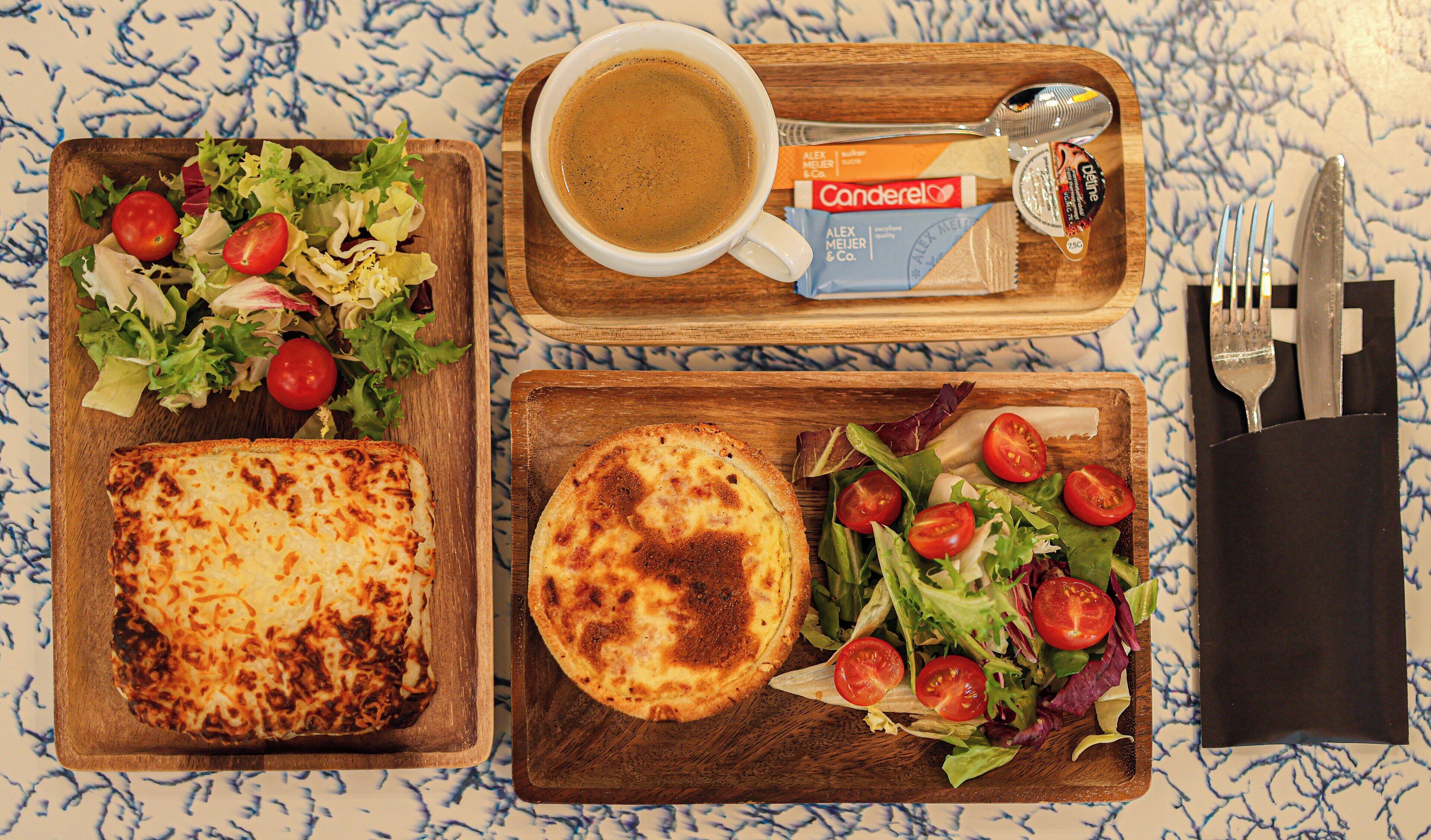A meal tray with a sandwich, a salad, a cup of coffee, and condiments.