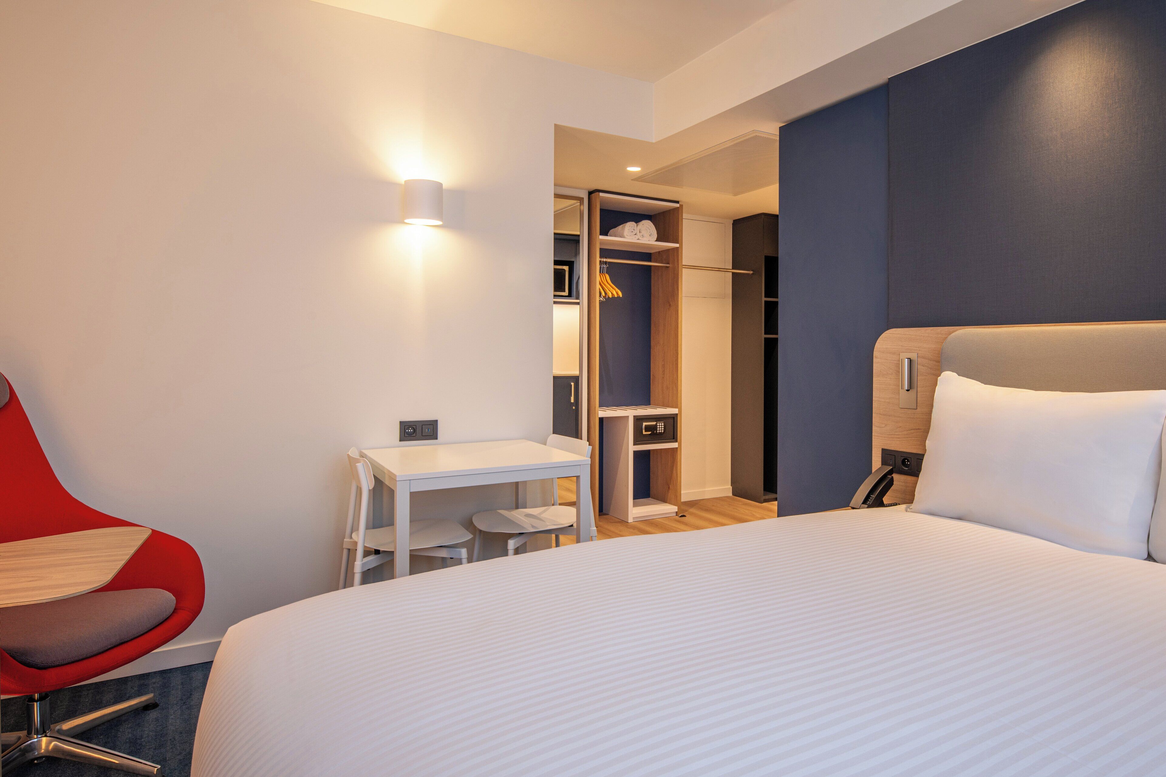 Habitación de hotel con cama, escritorio, silla, armario y vestidor.