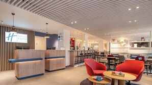A modern hotel lobby with a reception desk, seating area, and a bar. - Holiday Inn Express & Suites Ghent by IHG (Ghent)