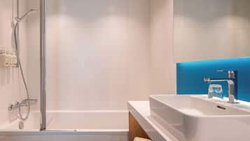 Een moderne badkamer met een bad, een douche en een wastafel, met een blauwe accentmuur.
