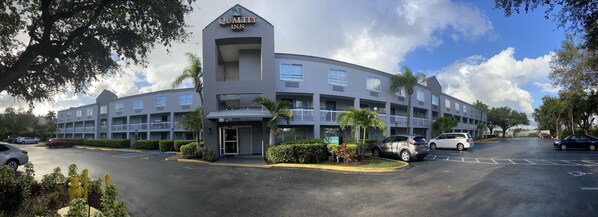 Un hotel de varios pisos con diseño moderno, que cuenta con un vestíbulo amplio y varios espacios de estacionamiento.