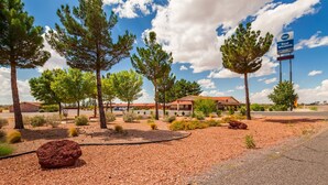 A Best Western hotel with a red-brick building, surrounded by landscaped gardens and tall trees. - Best Western Deming Southwest Inn (Deming)
