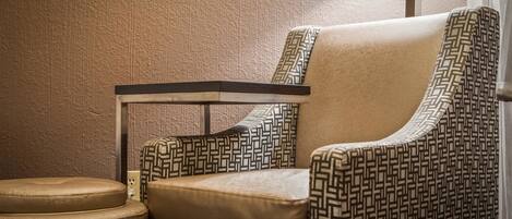 Une chaise recouverte d’un tissu à motifs géométriques, un pouf rembourré et une structure en métal.