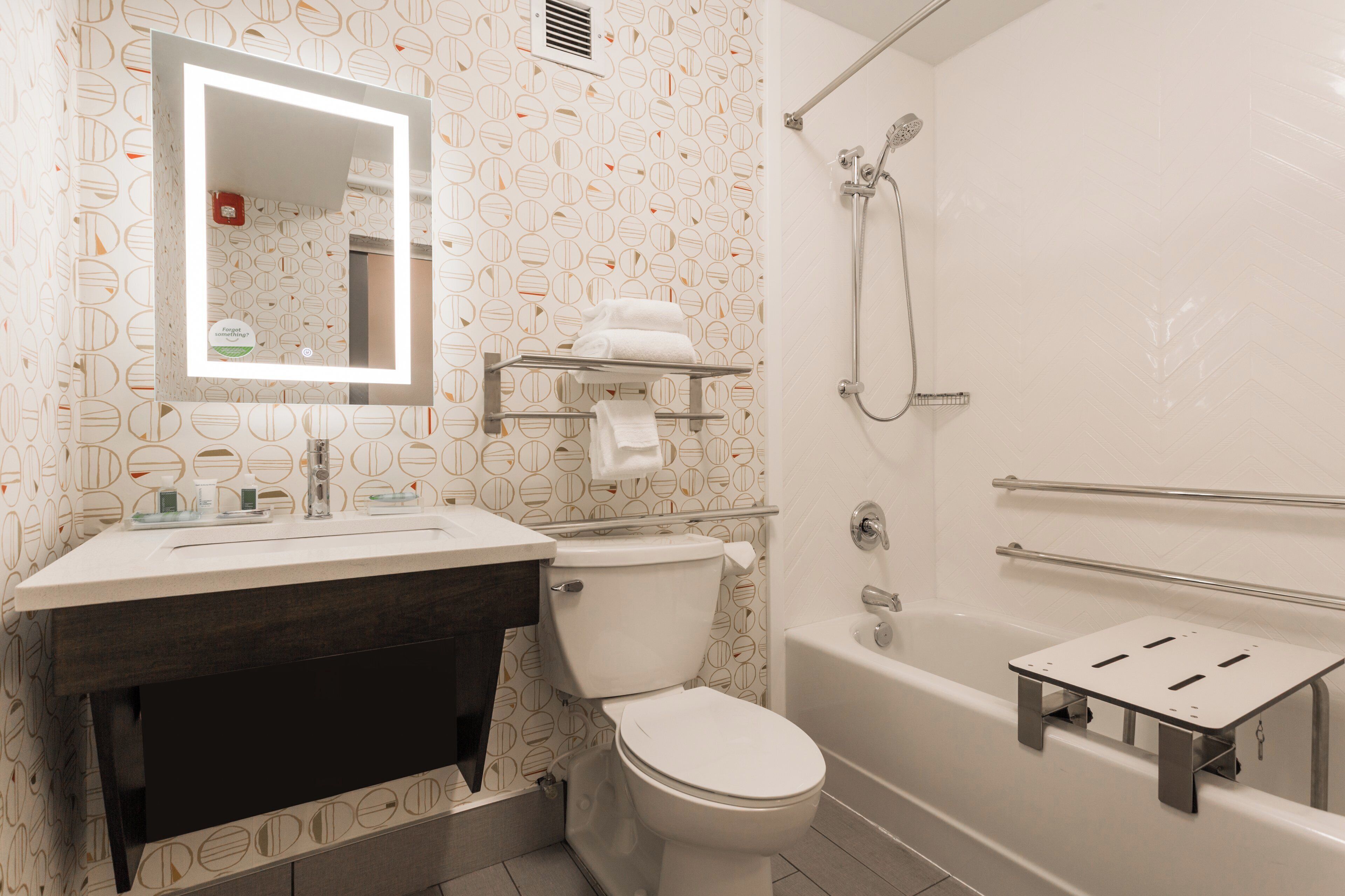 Un baño con inodoro, lavabo, espejo y ducha.