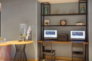 A modern workspace with two computer monitors, a wooden desk, and a round table with a decorative lamp.