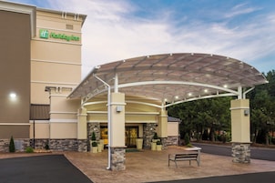 Entrada de un hotel Holiday Inn con un patio cubierto y pilares de piedra.