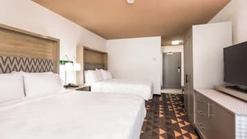 Een hotelkamer met twee bedden, een televisie, een bureau met een lamp en een kamer met een vloerbedekking.