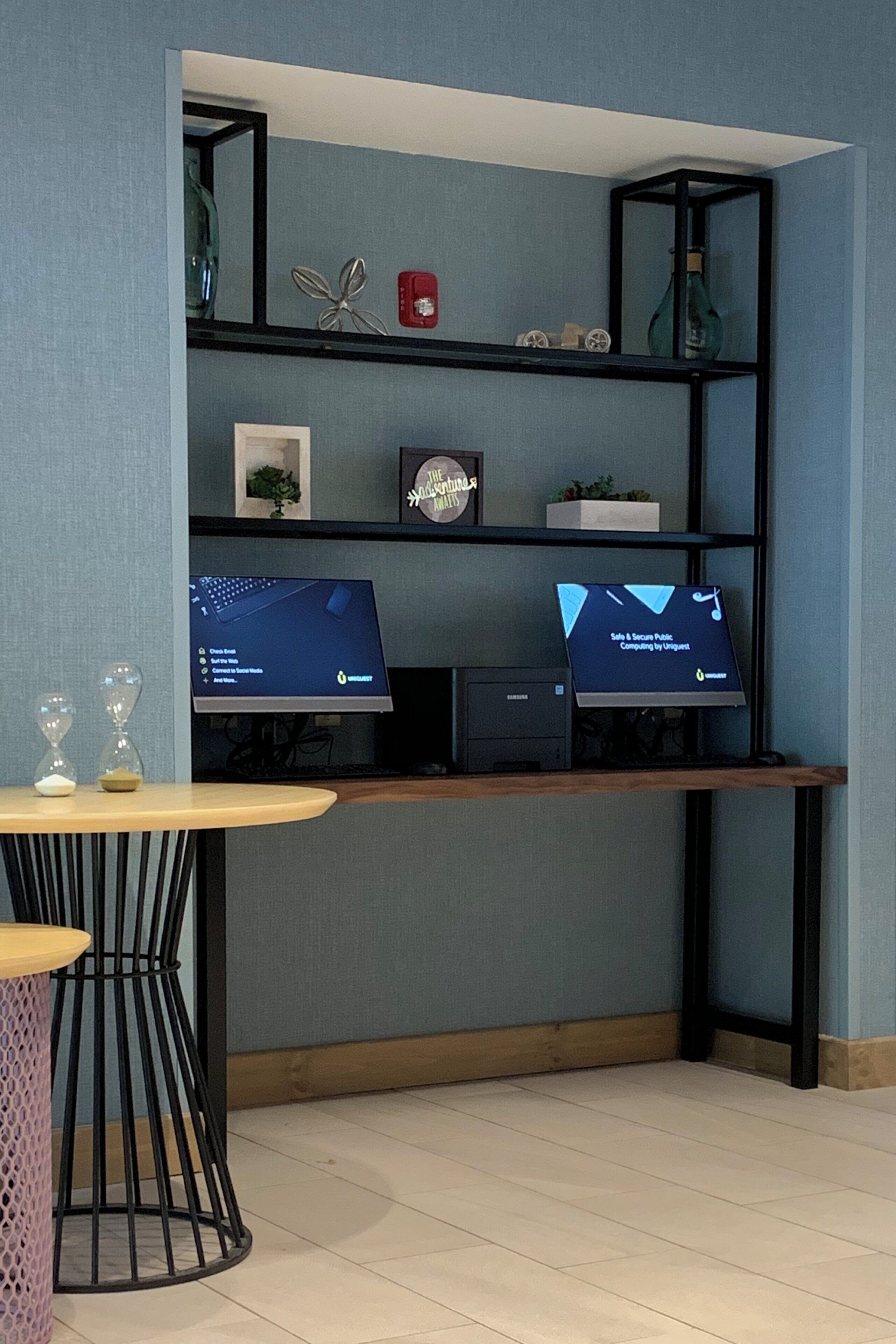 A modern room with a desk, two monitors, a small plant, and decorative items.
