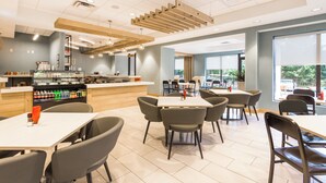 A modern cafe with a counter, seating area, and large windows. - Holiday Inn Boone - University Area by IHG (Boone)