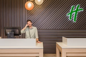 Un mostrador de recepción con diseño moderno, un letrero iluminado grande y un monitor de computadora.