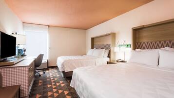 Habitación de hotel con dos camas, un escritorio con computadora y una silla.